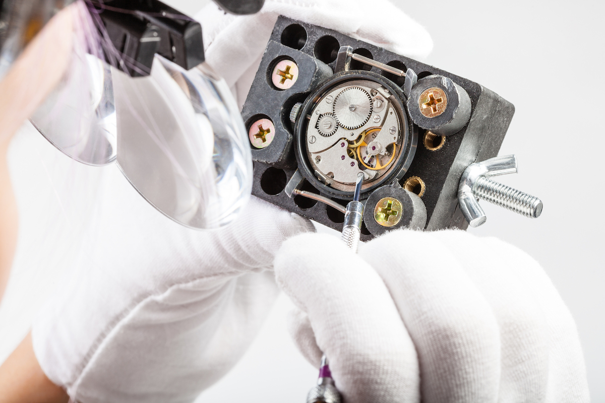 watchmaker in magnifying glasses repairs old watch